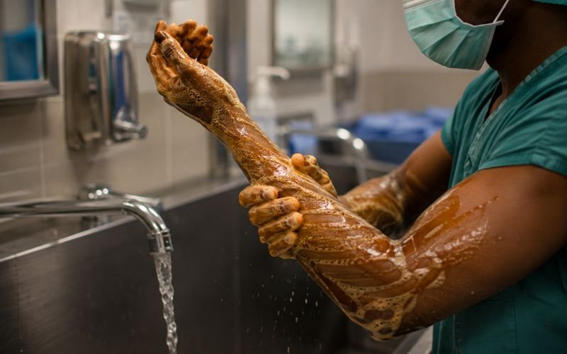 African surgeon washing his hands with iodophor surgical scrub at a sink