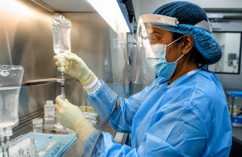 Oncology pharmacist safely preparing chemotherapy infusion under biosafety cabinet